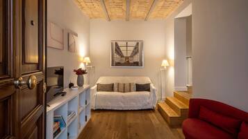 Ein gemütliches Zimmer mit Holzboden, einem weißen Sofa, einem roten Sessel und einem Bücherregal.