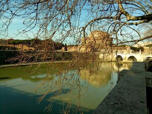 Eine Brücke mit Bögen über einem ruhigen Fluss, umgeben von Gebäuden und Bäumen.