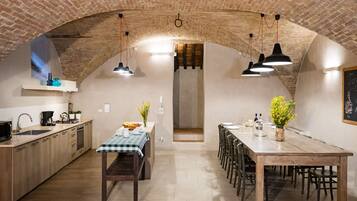 Una cucina rustica con pareti in mattoni a vista, un tavolo da pranzo in legno e illuminazione a sospensione.