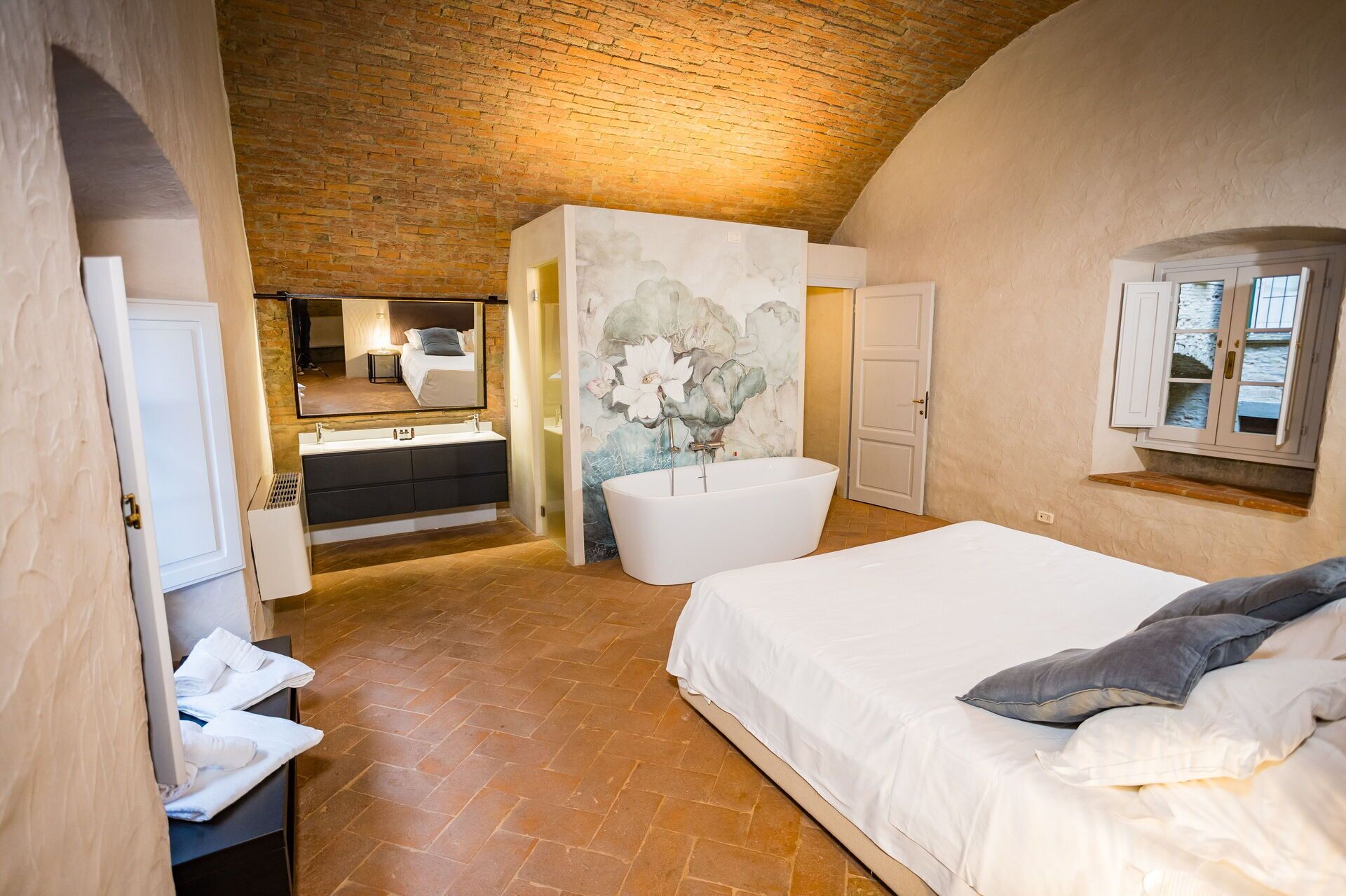 Una camera da letto con un letto grande, un bagno con vasca, uno specchio e una finestra con vista.