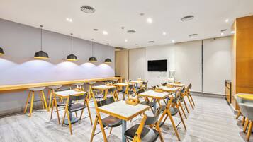 Un comedor moderno con mesas y sillas, luces empotradas en el techo y una pared decorativa de madera.