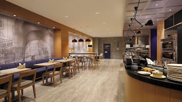 A restaurant with a counter, tables, chairs, and a mural on the wall.