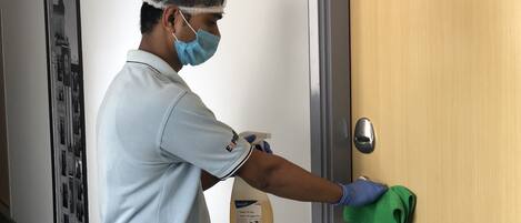 A person cleaning a door with a green cloth and a spray bottle.