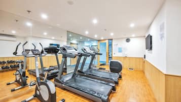 Un gimnasio con cintas de correr, elípticas y mancuernas.