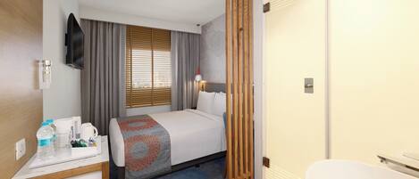 A hotel room with a bed, bedside table, and a bathroom.