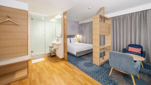 Ein Hotelzimmer mit Bett, Schreibtisch, Stuhl und Kleiderschrank.