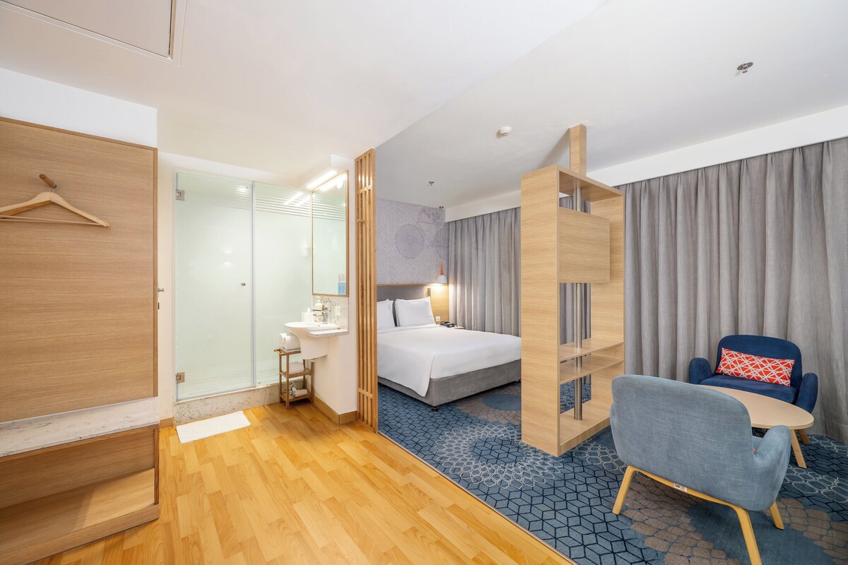Een hotelkamer met een bed, een bureau, een stoel en een kledingkast.