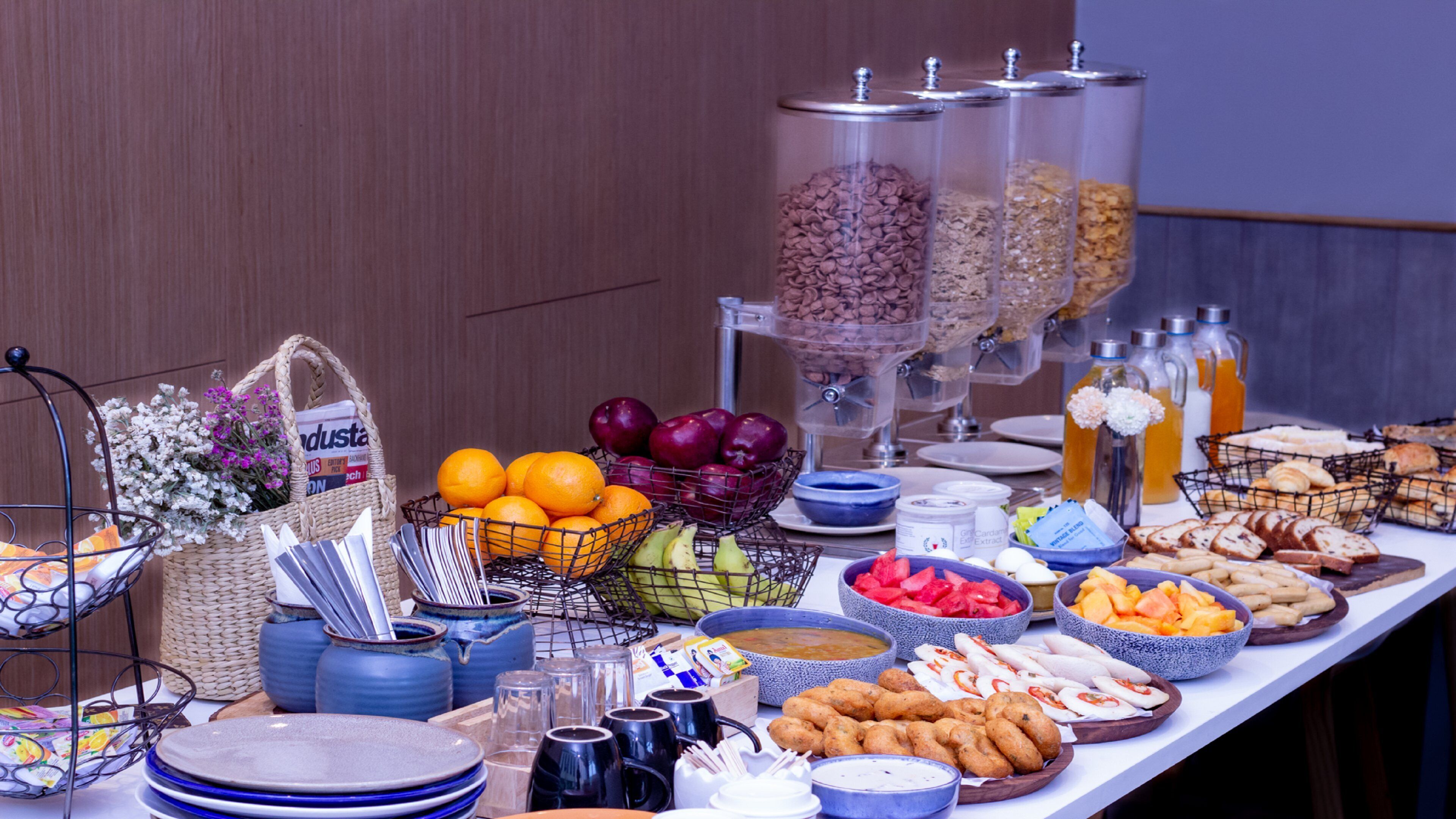 Un tavolo per buffet con diversi cibi, tra cui frutta, dolci e bevande.