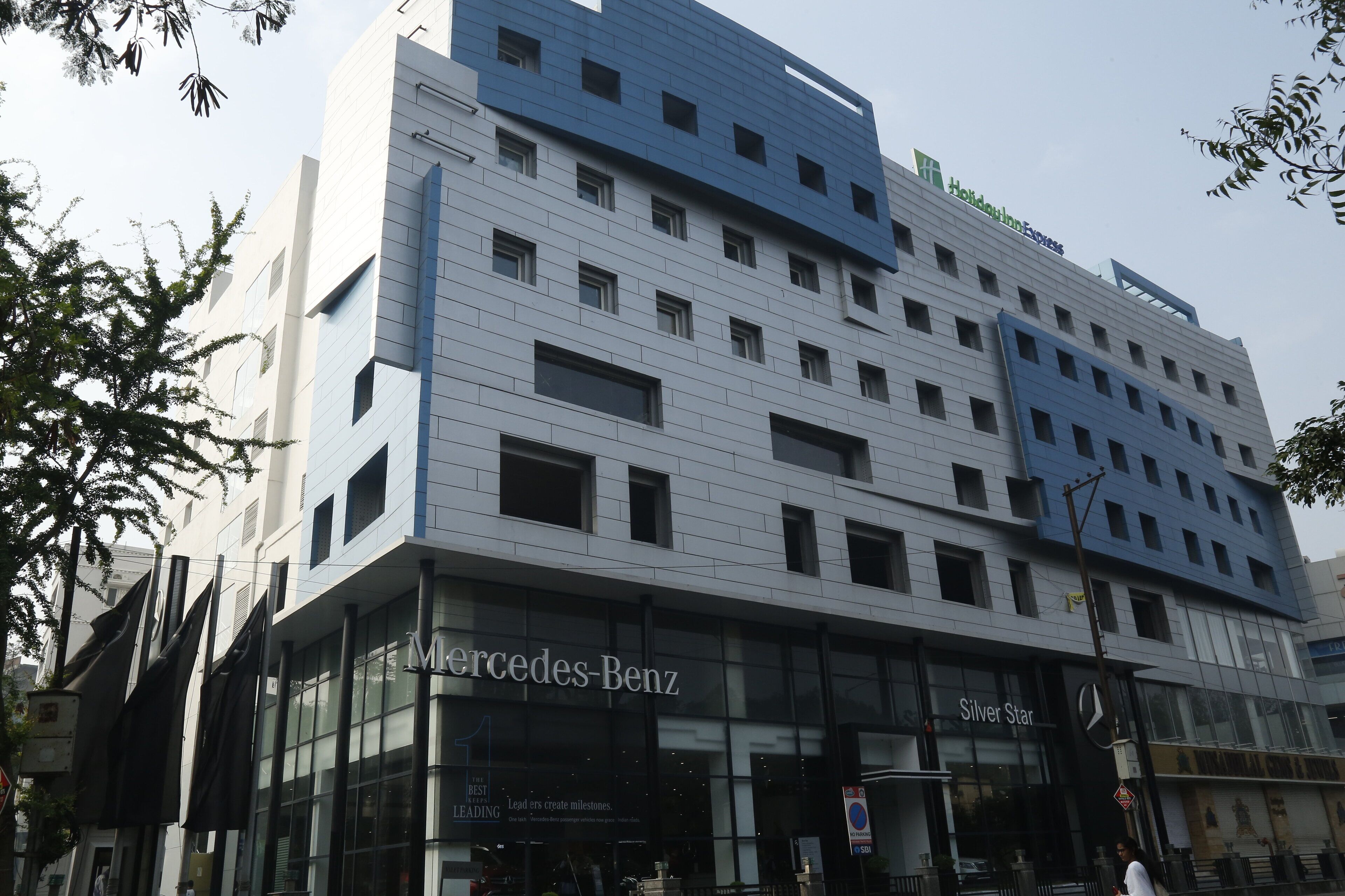 Een modern hotelgebouw met een opvallende Mercedes-Benz winkel op de begane grond.