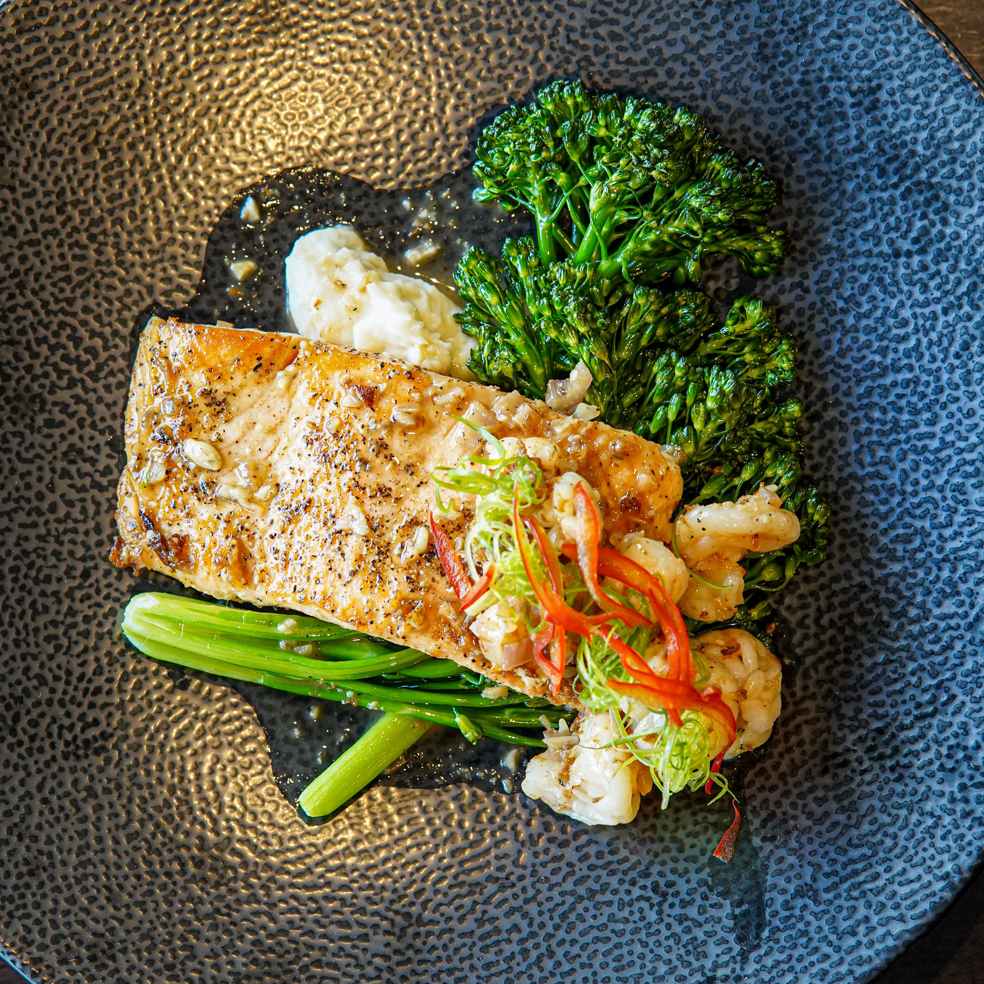 En tallerken mad med fisk, broccoli og blomkål.