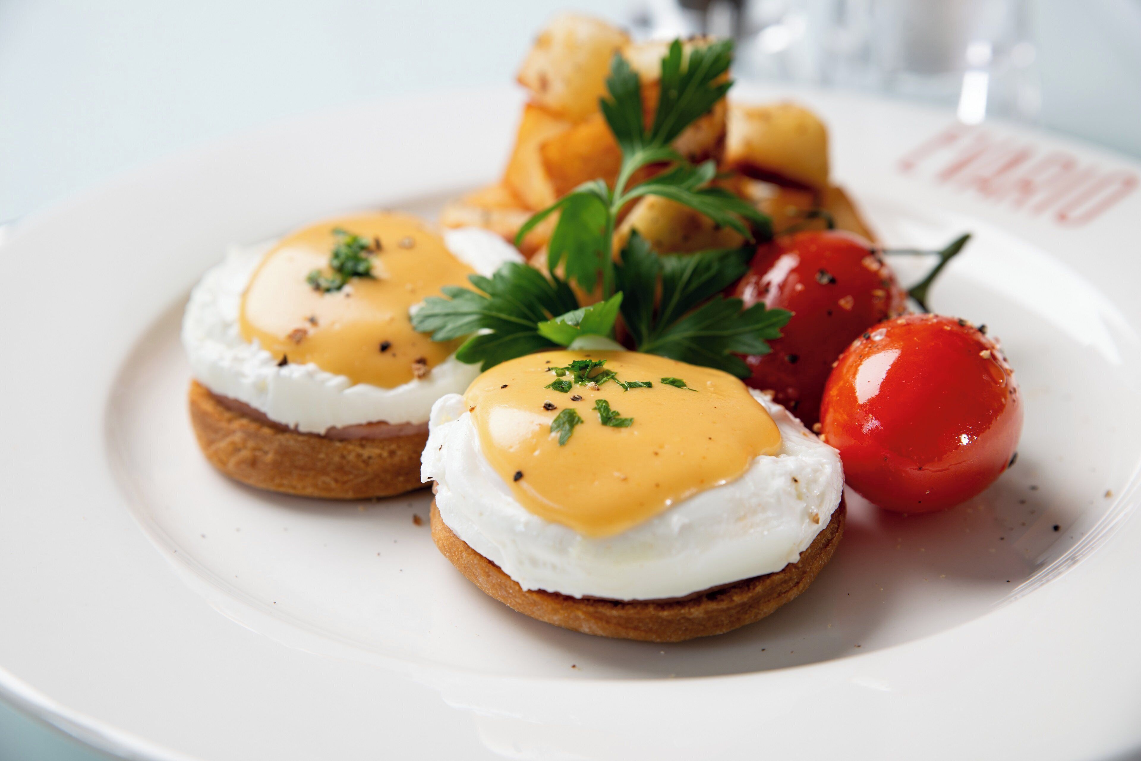 A plate with eggs benedict and cherry tomatoes.