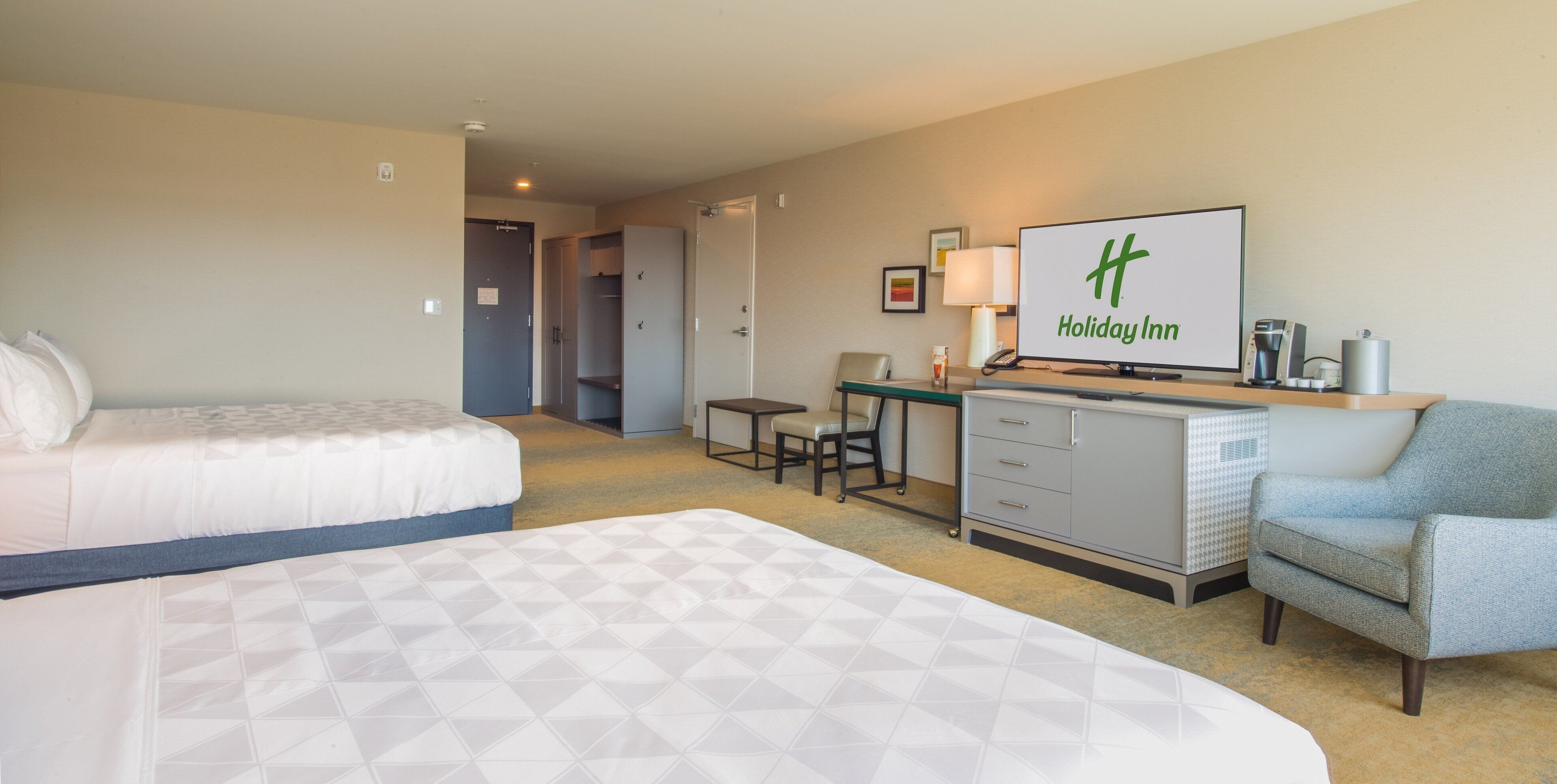 Une chambre d’hôtel avec deux lits, un bureau, une chaise, une télévision et une machine à café.