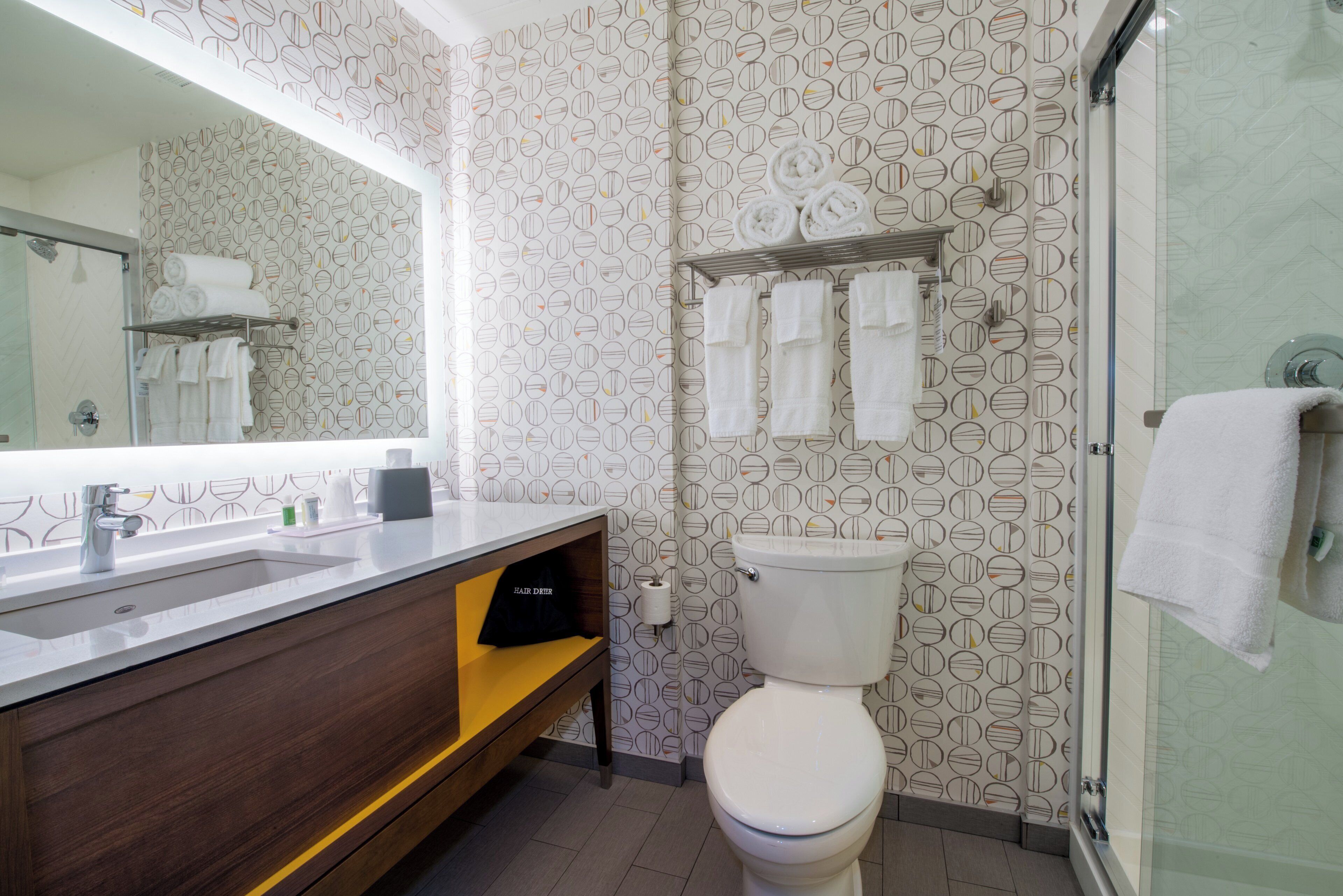 A bathroom with a toilet, a sink, a mirror, and a shower.