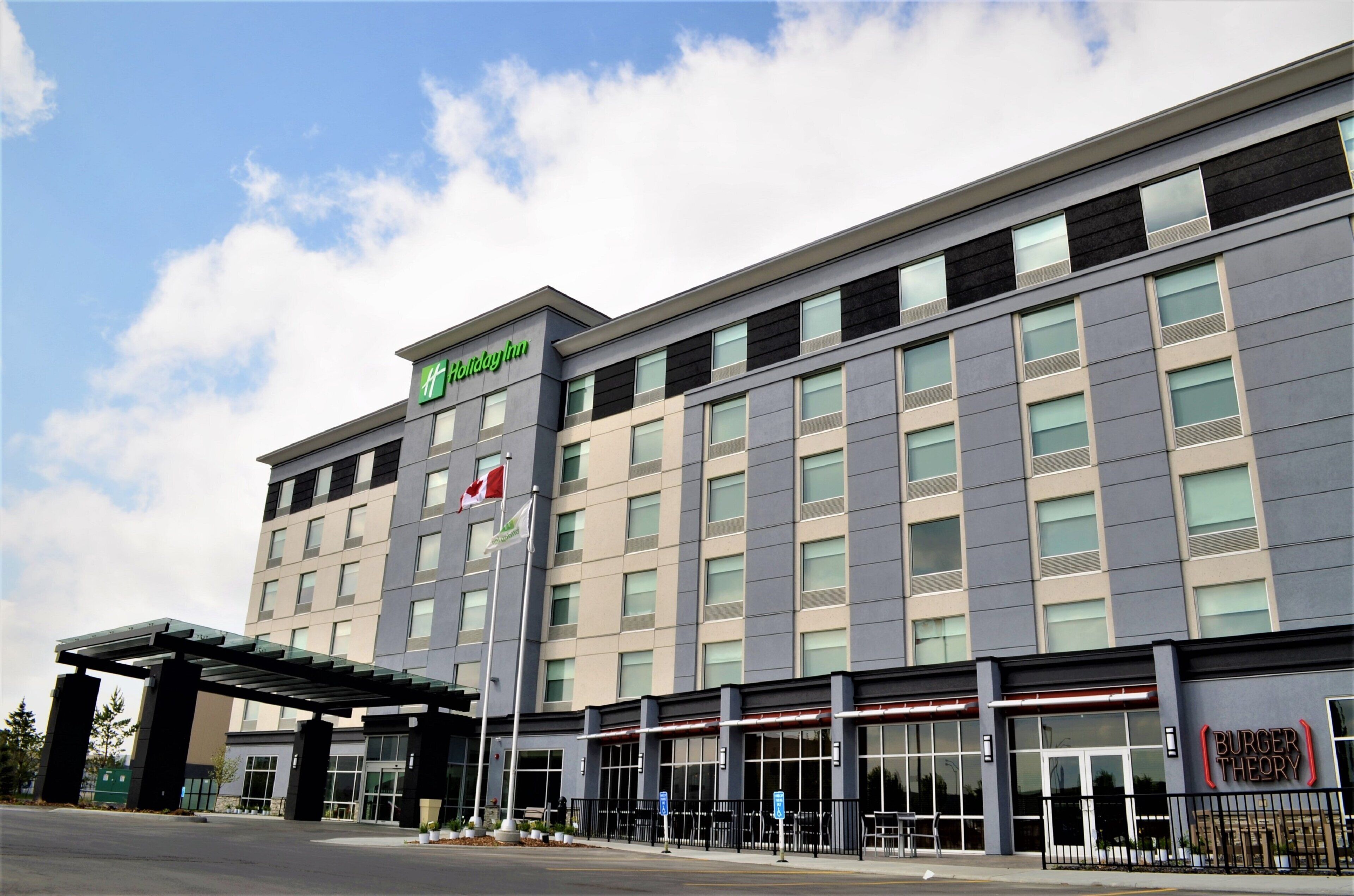 Un hôtel Holiday Inn doté d’une façade moderne, de nombreuses fenêtres et d’un mât pour drapeau.