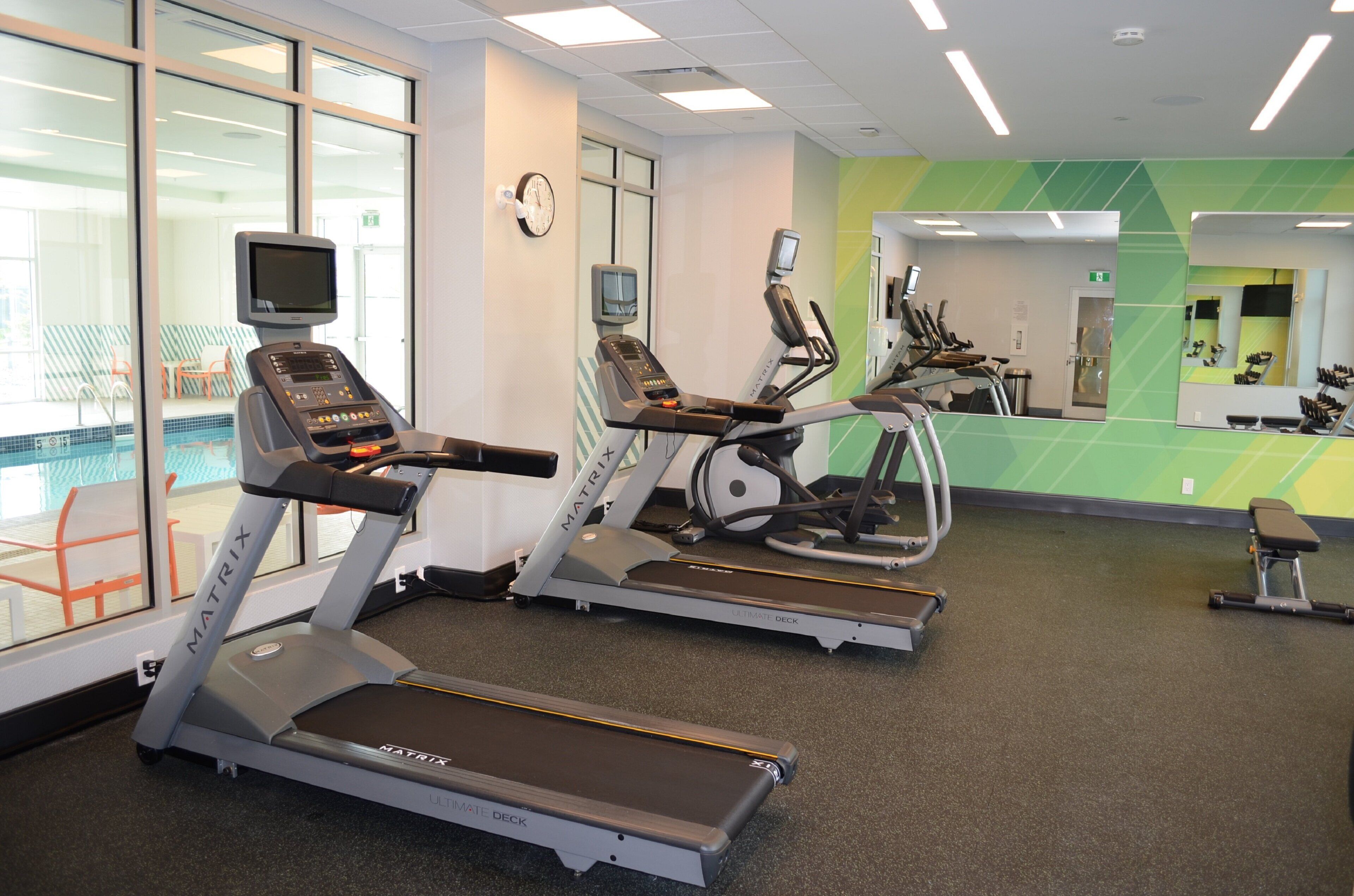 A gym with treadmills, exercise bikes, and a mirrored wall.
