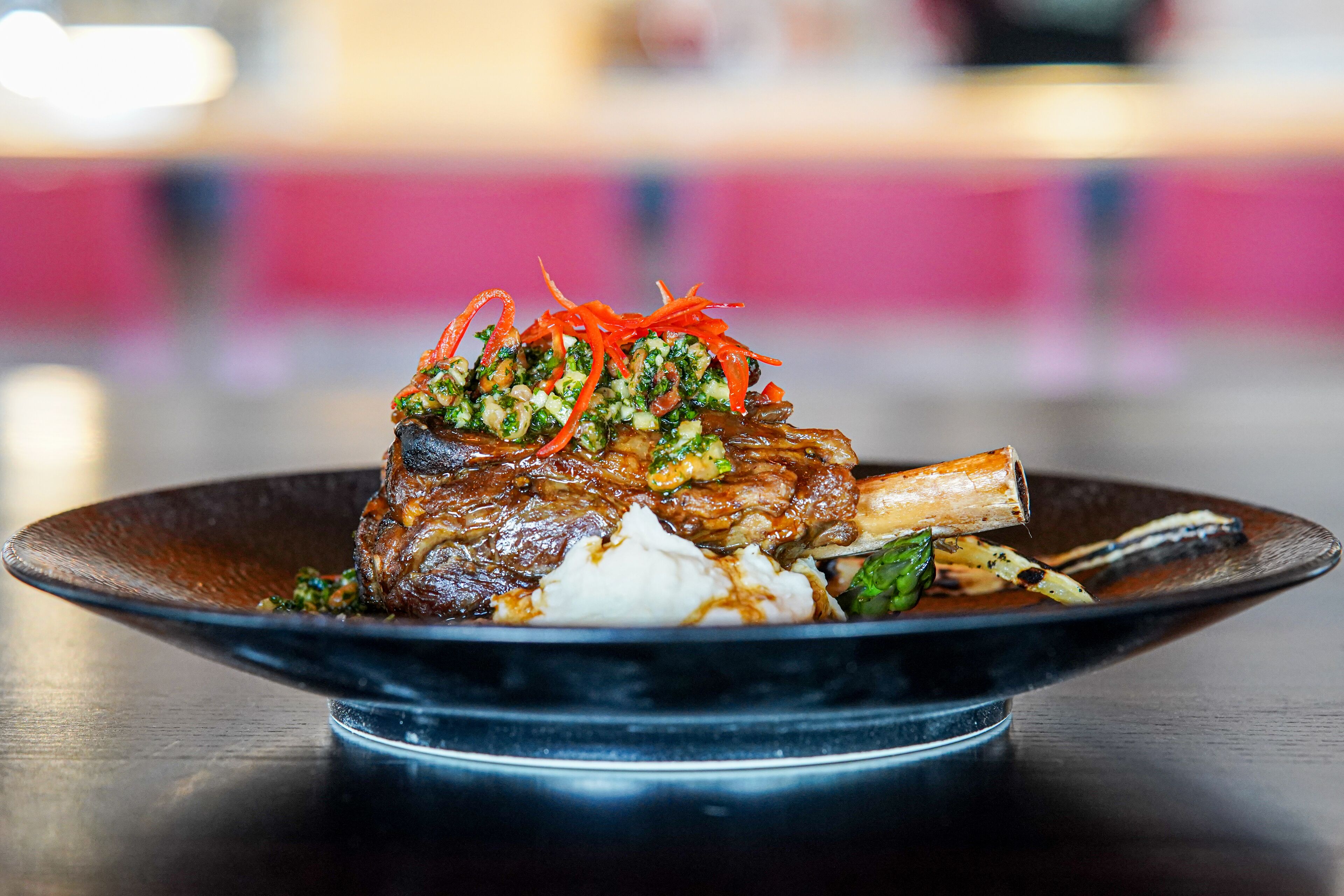 A plate of food with a large piece of meat, vegetables, and a garnish.