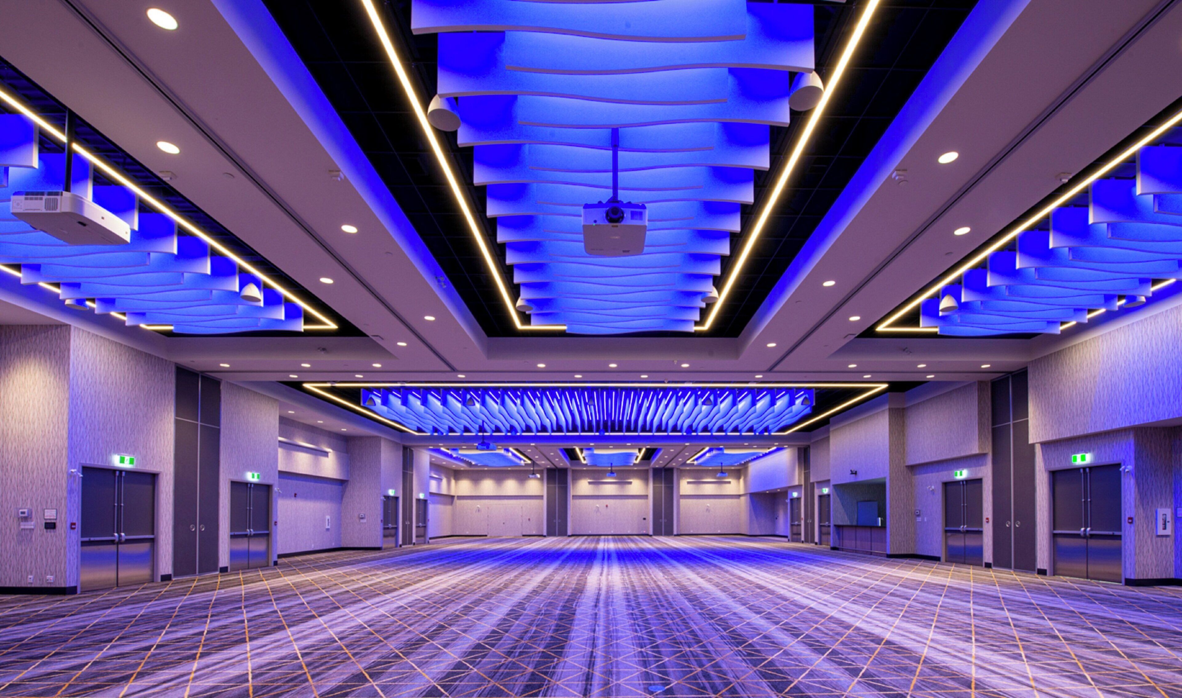 A spacious conference room with a patterned carpet, recessed lighting, and a modern ceiling design.