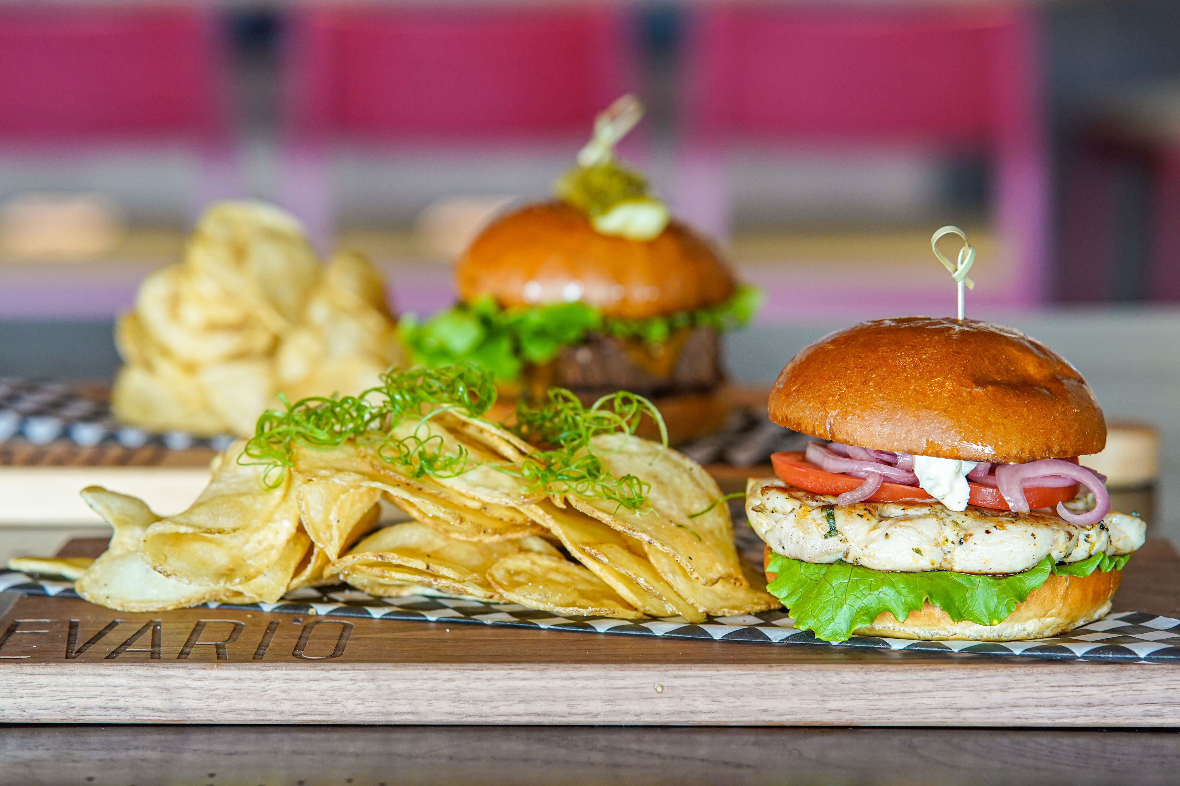 A burger with lettuce, tomato, and a bun on a wooden board.