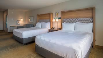A hotel room with two beds, a bedside table with a lamp, and a wall-mounted telephone.