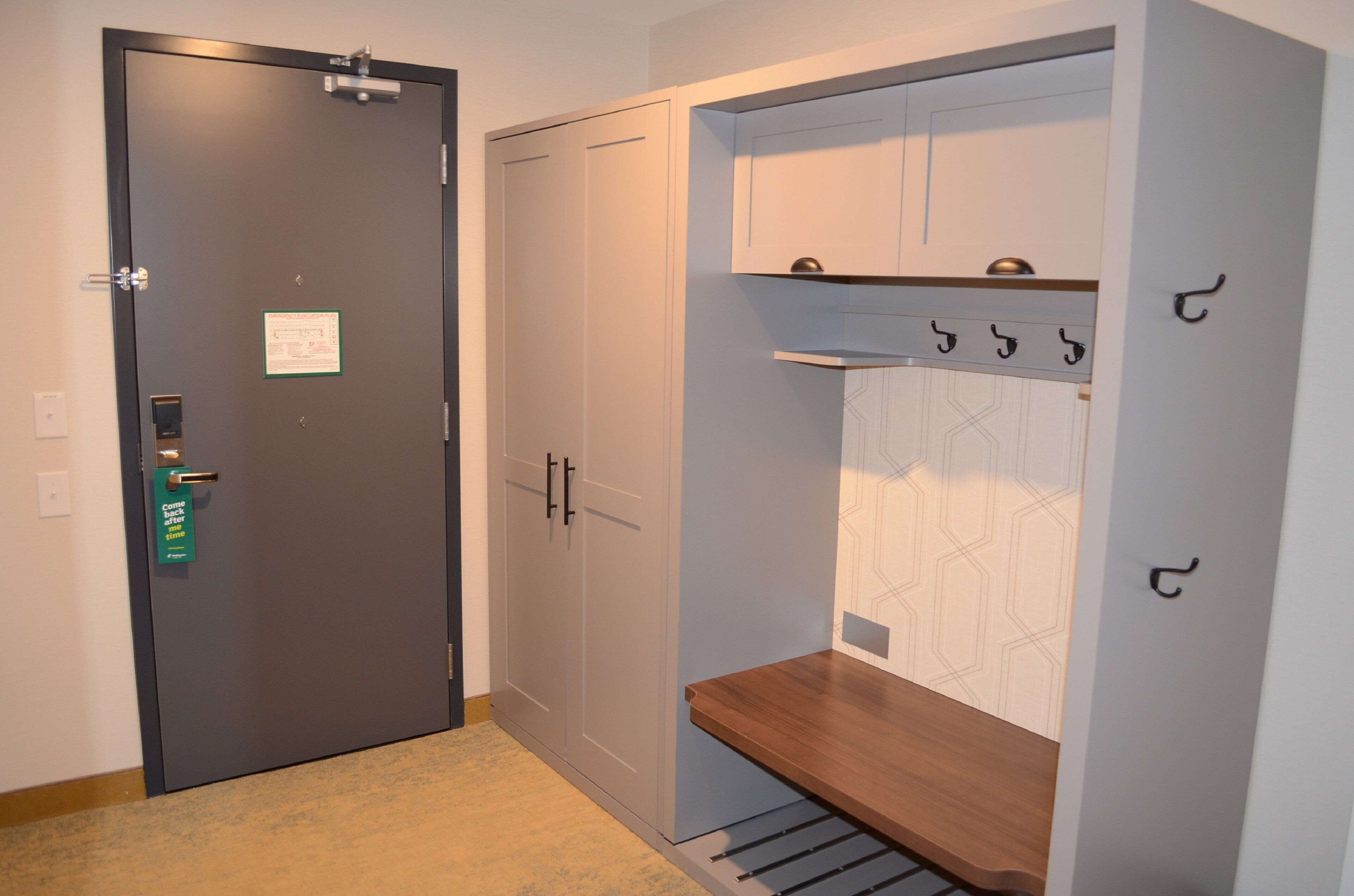 A room with a door, a coat rack, and a bench.