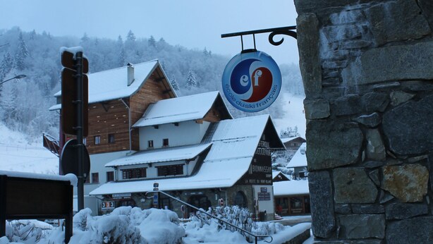 A snow-covered building with a stone wall and a sign indicating a ski resort. - Very nice apartment skis Chamonix Valley (Les Houches)