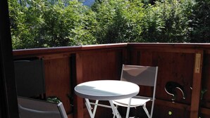 A patio with a round table and two chairs, overlooking a mountainous landscape. - Very nice apartment skis Chamonix Valley (Les Houches)