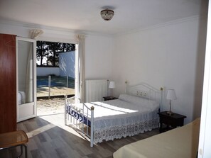 A bedroom with a bed, bedside tables, a chair, and a view of the outside.