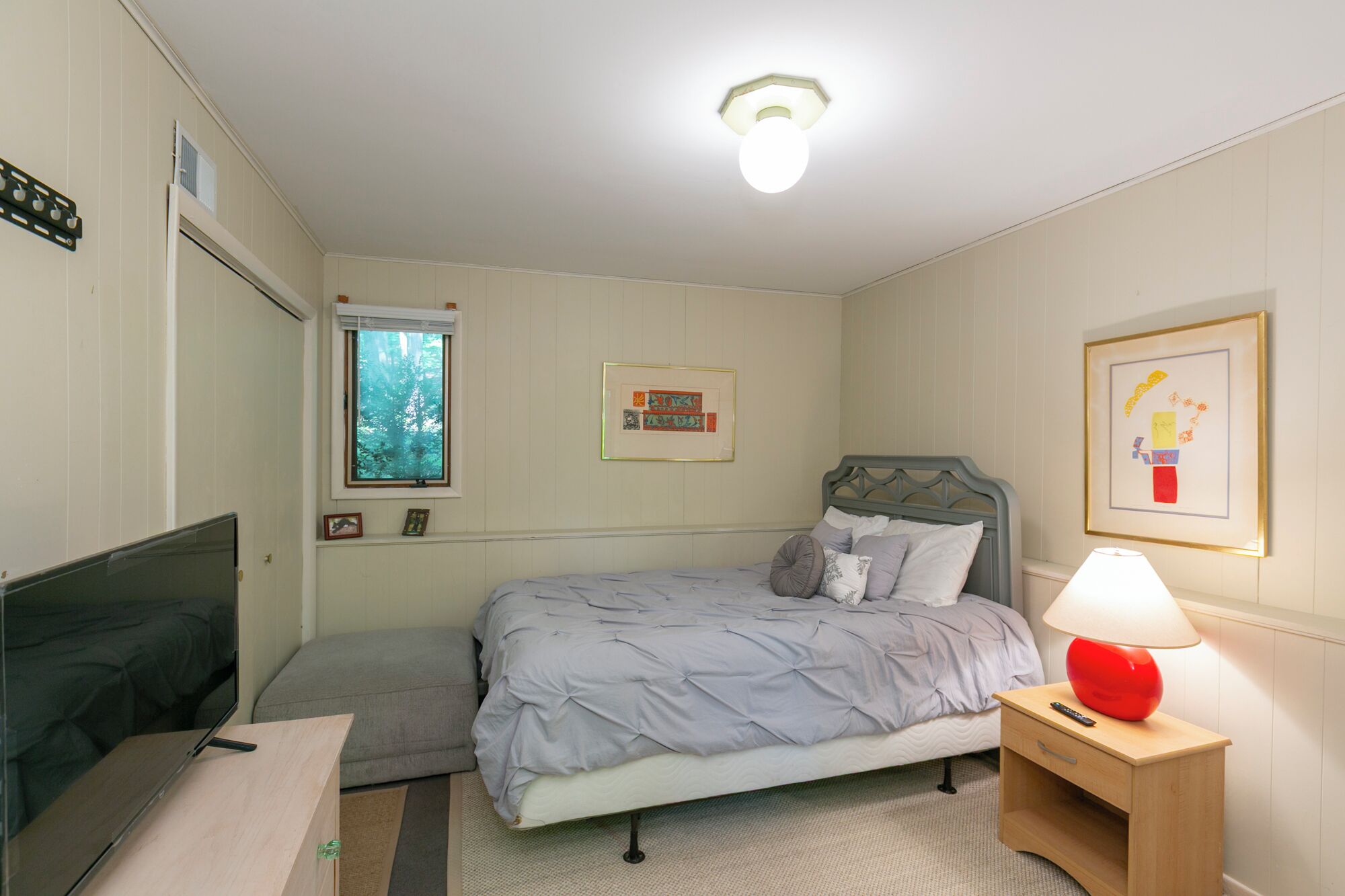 Un dormitorio con cama, mesita de noche, lámpara y ventana con persianas.