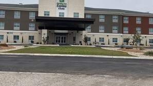 A Holiday Inn Express & Suites building with a modern design, featuring a central entrance with a covered walkway, multiple windows, and a landscaped front yard. - Holiday Inn Express & Suites Junction by IHG (Junction)