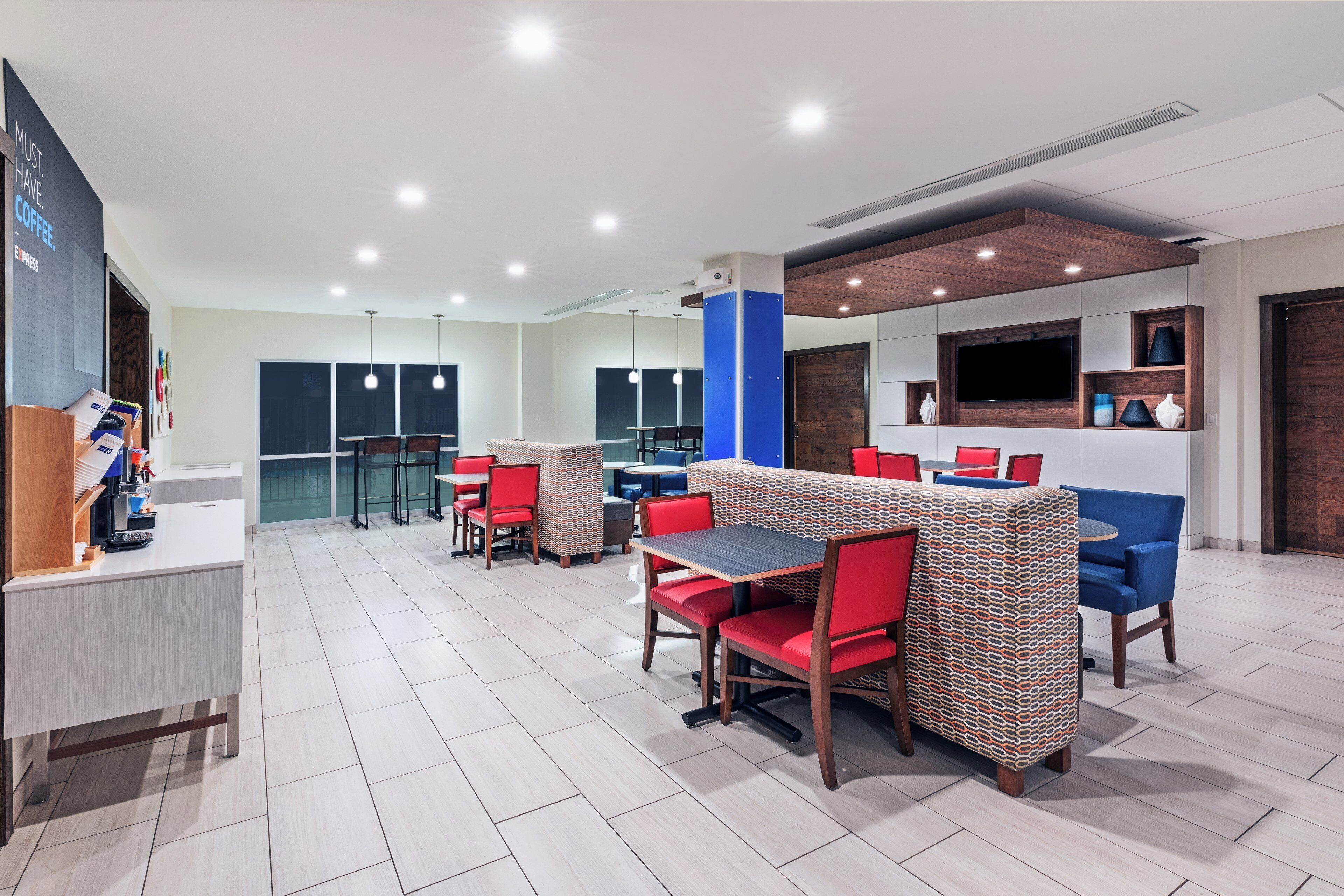 A modern cafe with multiple seating areas, including tables and booths, and a coffee machine on the counter.