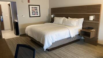 A hotel room with a bed, a nightstand, a chair, and a framed picture on the wall.