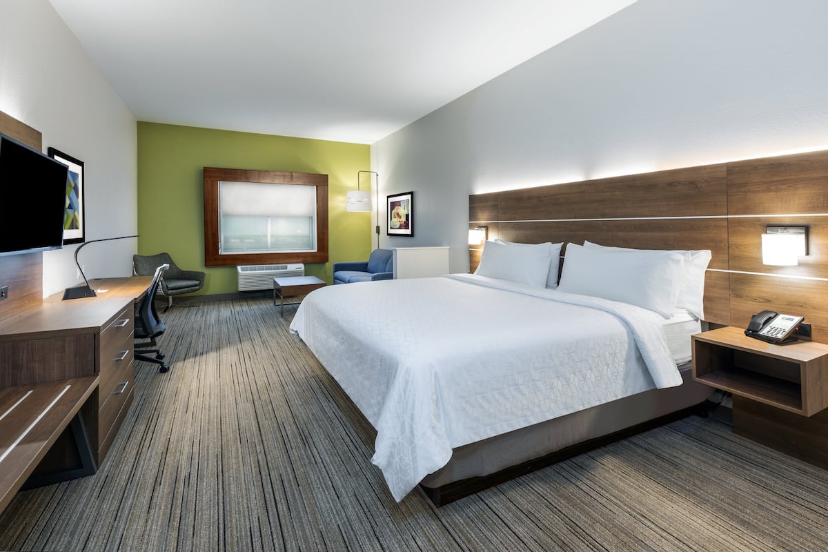 A hotel room with a bed, desk, chair, and a television.