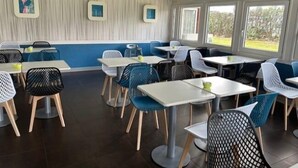 A dining area with tables and chairs, a blue and white color scheme, and framed pictures on the wall. - Hôtel Ibis Budget Nantes Ouest Atlantis Couëron (Coueron)