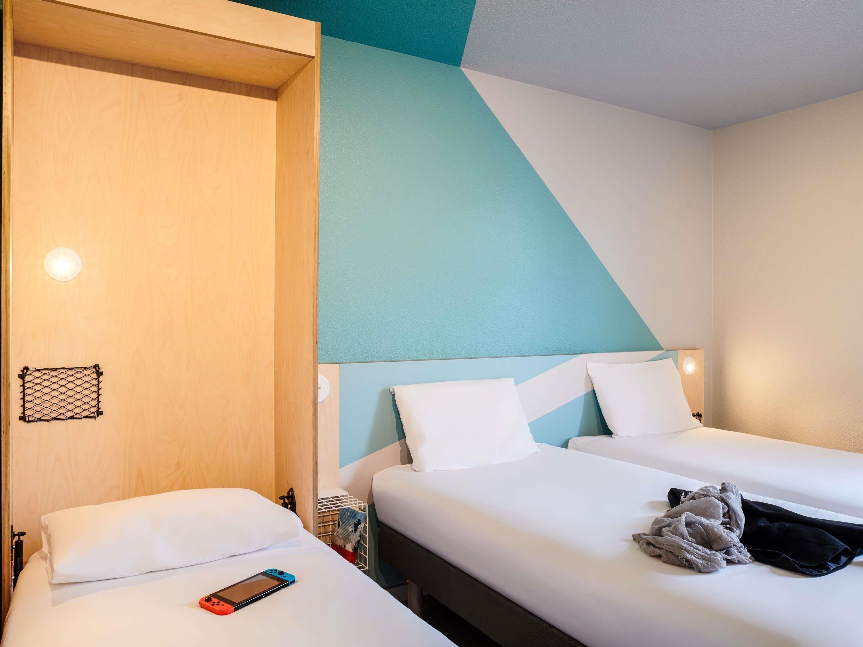 Een hotelkamer met twee bedden, een houten deur en een wand in een blauwgroene tint.