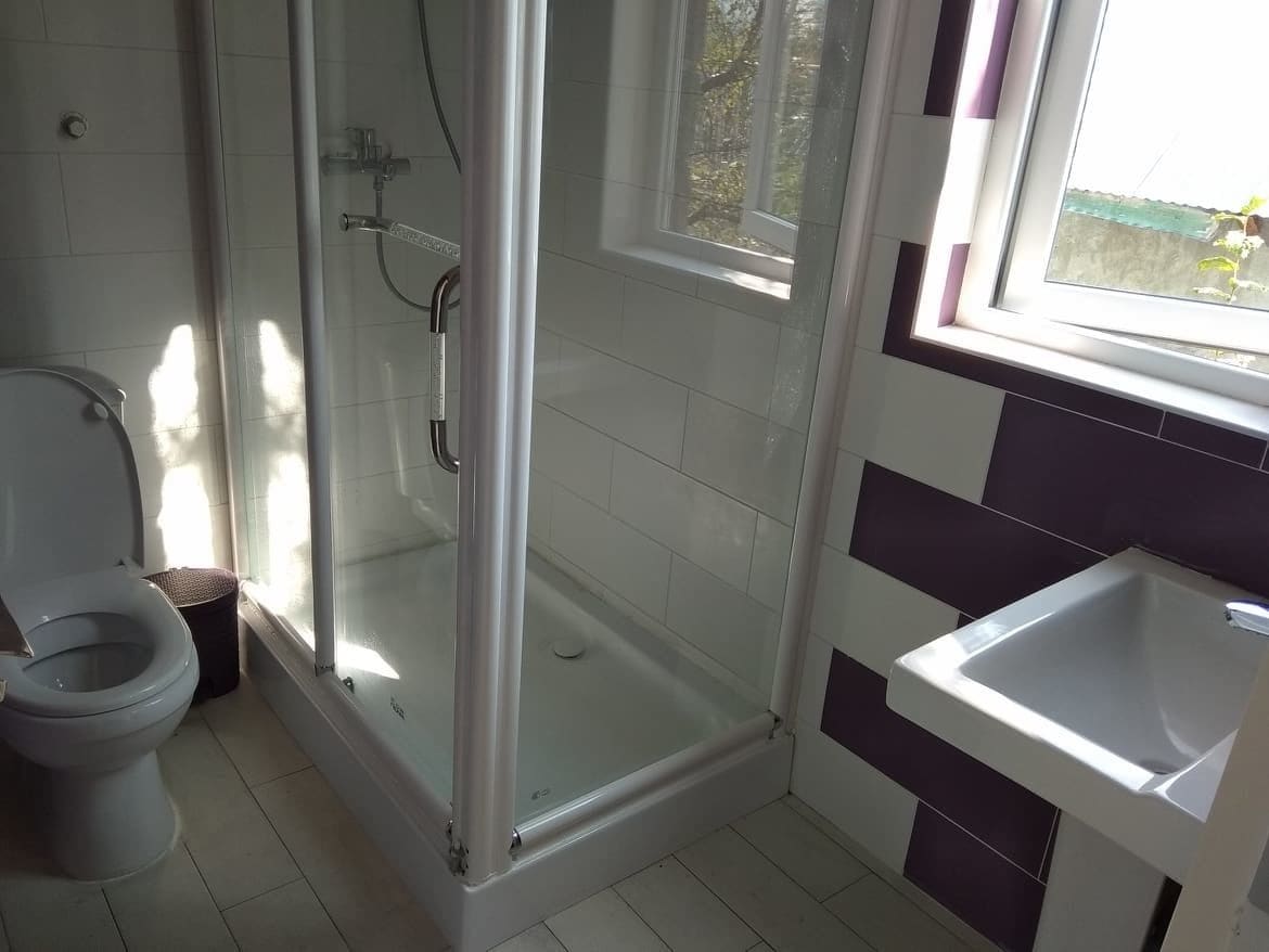 Een badkamer met een douchecabine, toilet en wastafel.