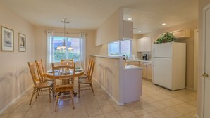 A modern kitchen with a central island, white cabinetry, and a refrigerator. - "The Fontana" 4bedrooms,  Hot Tub, Patio Mister,Pets Welcome, 5G Fiber Internet! (Albuquerque)
