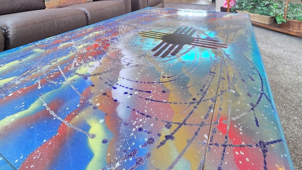 A living room with a colorful abstract coffee table, a brown leather sofa, and a flat-screen TV. - "The Fontana" 4bedrooms,  Hot Tub, Patio Mister,Pets Welcome, 5G Fiber Internet! (Albuquerque)