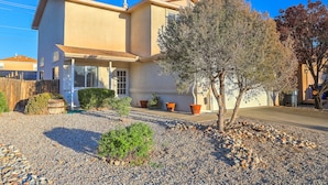 A two-story house with a front porch, a small tree, and a gravel driveway. - "The Fontana" 4bedrooms,  Hot Tub, Patio Mister,Pets Welcome, 5G Fiber Internet! (Albuquerque)