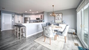 Una cocina moderna con armarios blancos, una isla central y taburetes de bar.
