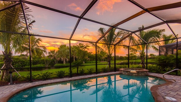 A swimming pool with a view of palm trees and a sunset.