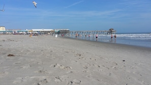 A beach with a pier extending into the water, featuring a restaurant and a viewing platform.