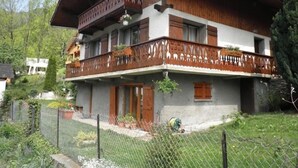 A two-story wooden house with a balcony, surrounded by a fence and greenery. - BEAUTIFUL CHARMING SAVOYARD CHALET ,, 3 * WIFI   (Villard-sur-Doron)