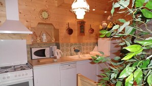 A compact kitchen with a stove, microwave, and dishwasher, wooden cabinets, and a hanging plant. - BEAUTIFUL CHARMING SAVOYARD CHALET ,, 3 * WIFI   (Villard-sur-Doron)