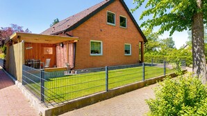 A two-story brick house with a covered patio and a fenced yard.