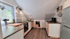 A compact kitchen with a wooden countertop, white cabinets, a built-in oven, and a refrigerator.