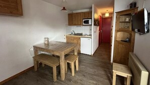 A compact kitchen with wooden cabinets, a microwave, and a small refrigerator.