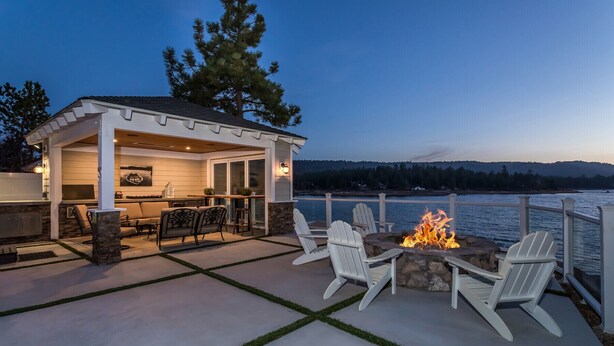 Un patio exterior con un brasero, asientos y vistas al lago al atardecer.