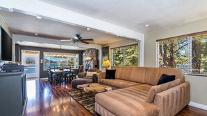 Amplia sala de estar con un sofá modular grande, una mesa de comedor y una zona de cocina.