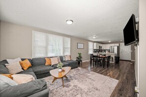 A living room with a sofa, coffee table, and a dining area with chairs and a table.