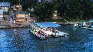A docked boat with a covered seating area and a small deck, surrounded by water.